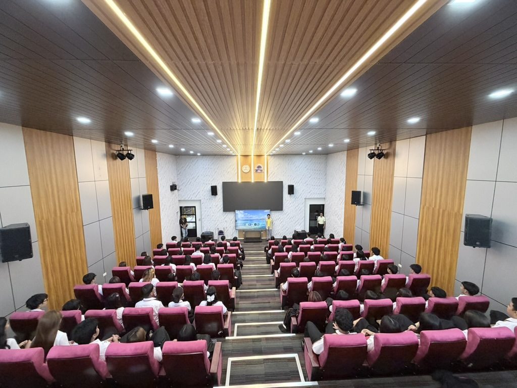 View from the stage of Arcinas Hall with every row filled, the centre aisle running to the back of the room.