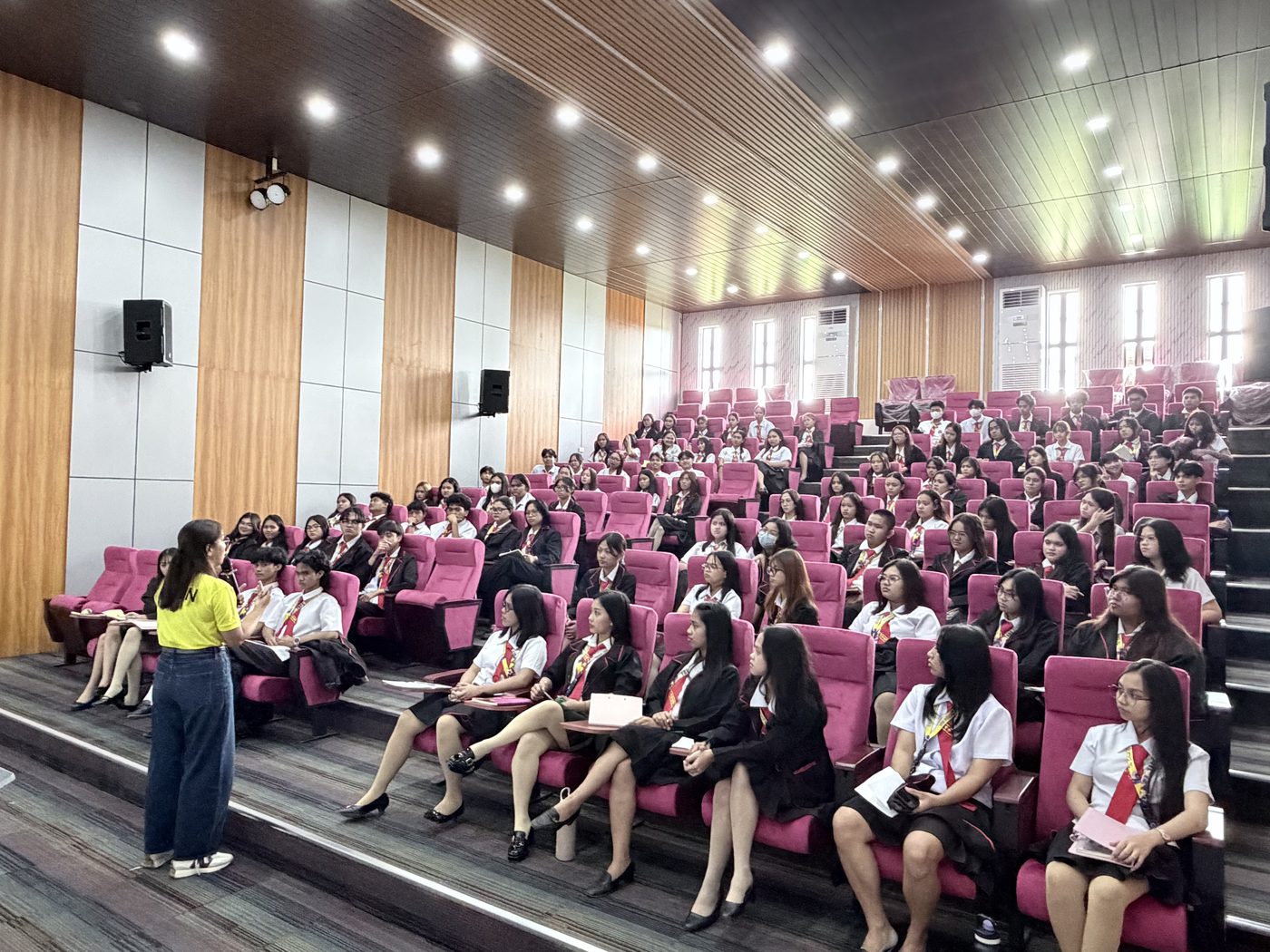 Guests seated in the mauve tiered seating of Arcinas Hall during a program.