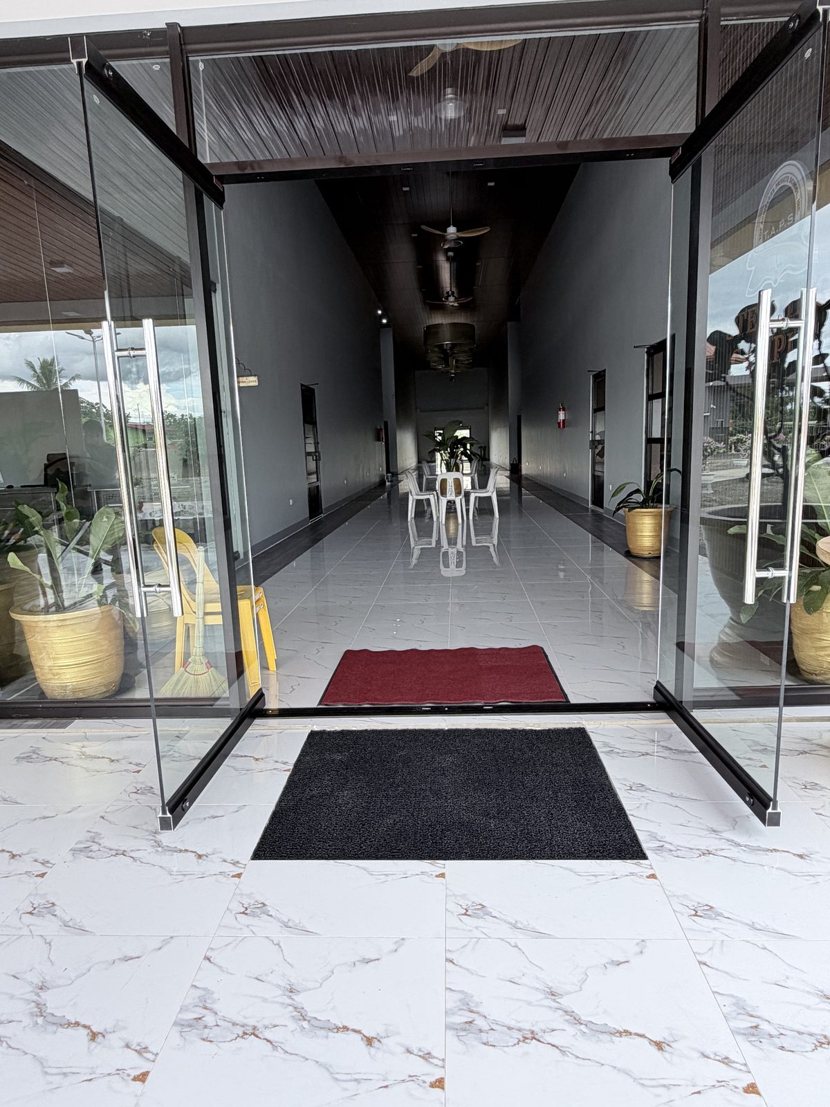 Glass double doors at the main entrance, opening onto a polished marble-tiled corridor.