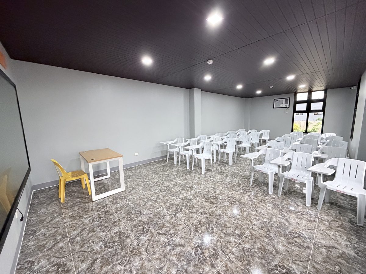 White stacking chairs arranged in rows across the marbled floor of the seminar room.