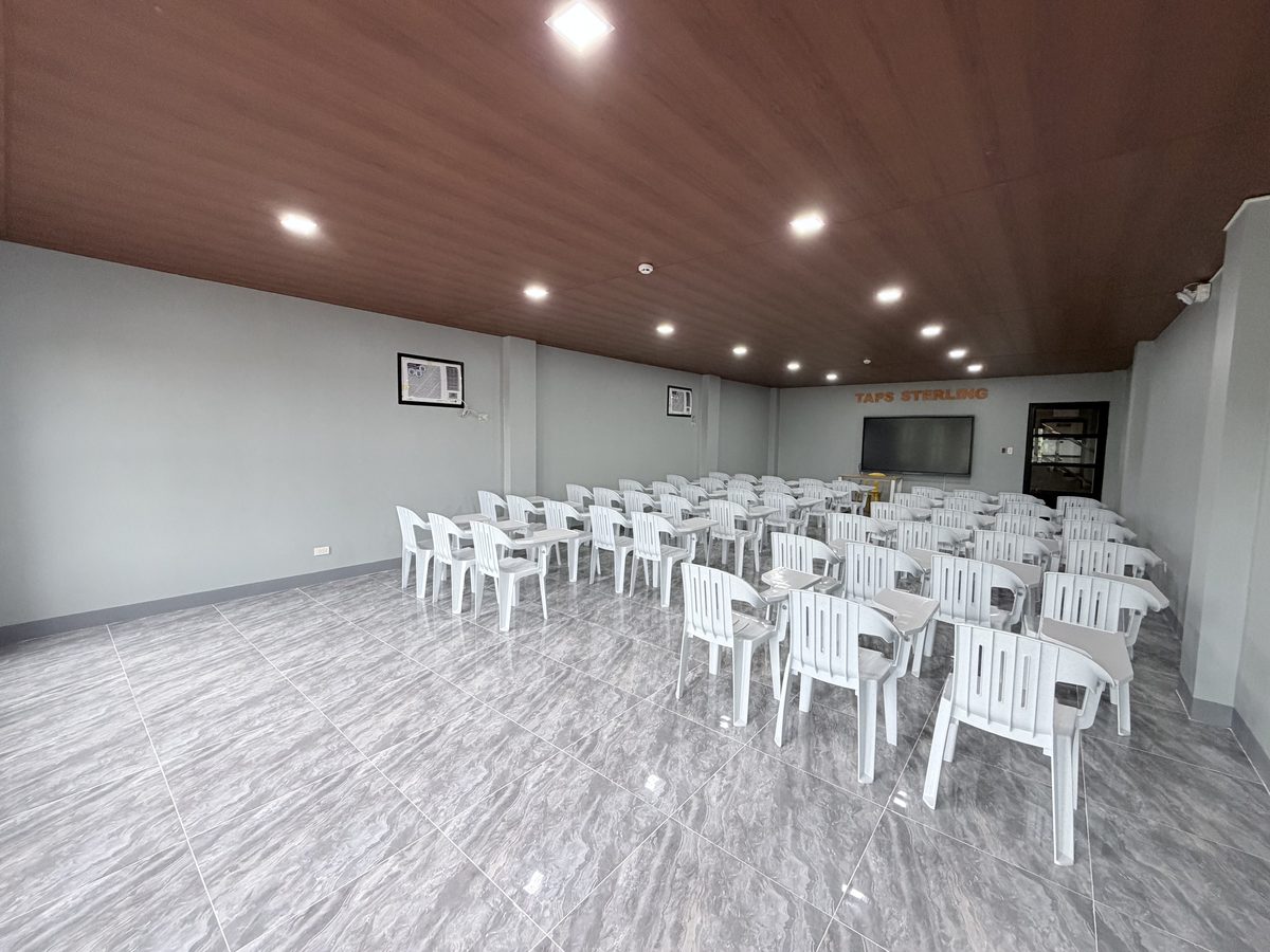The seminar room from the opposite corner, chairs set in rows beneath the timber ceiling.